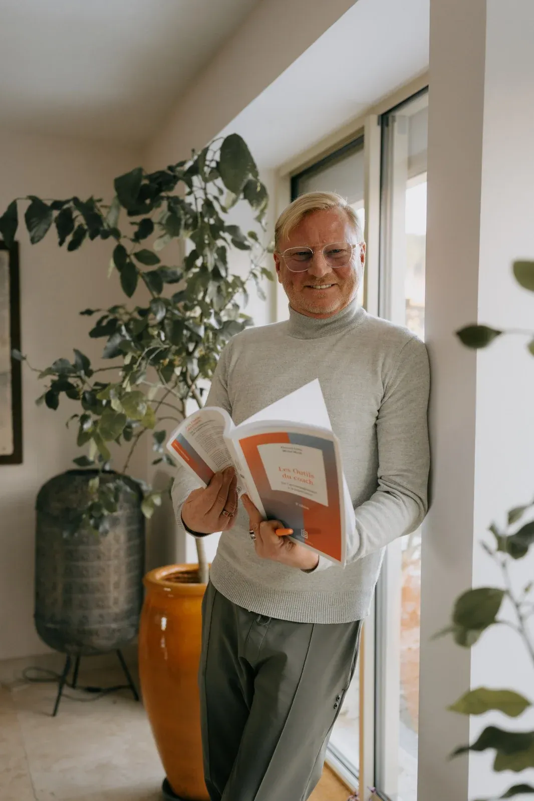 Édouard Gouvaert-Nouvelot, coach de vie, lisant dans un intérieur lumineux.